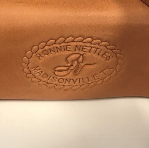 A leather bag with the logo of Ronnie Nettles on it, featuring Ronnie Nettle Stirrups 2" Varnished Leveler Style.