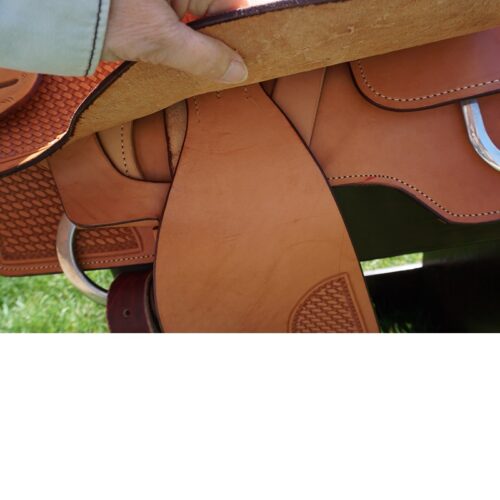 A person is putting a 16 1/2" Custom Reiner Saddle on a horse.