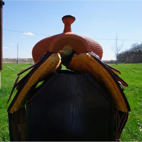 The 16 1/2" Custom Reiner Saddle is sitting on top of a wooden box.