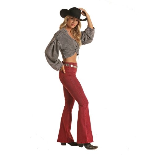 A woman donning a cowboy hat and flared jeans, exuding Rock n Roll Wine Bell Ladies Jean vibes.