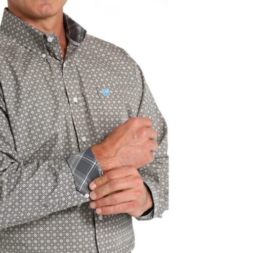 Man adjusting the sleeve of a patterned shirt.